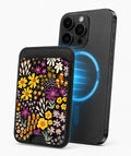 Black Folk Garden Floral MagSafe card holder attached to a compatible iPhone