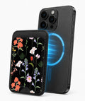 Black Wildflower Meadow MagSafe card holder attached to a compatible iPhone