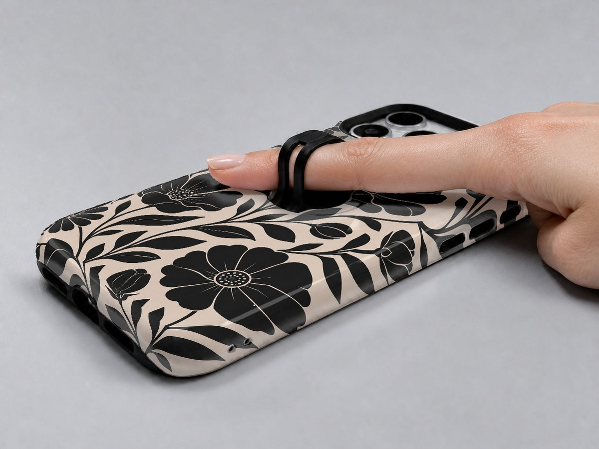 Black Cream Oversized Floral MagSafe Loop iPhone Case shown in use with a finger through the horizontal loop