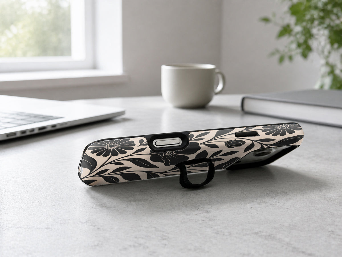 Black Cream Oversized Floral MagSafe Loop iPhone Case shown in a neutral white professional lifestyle setting