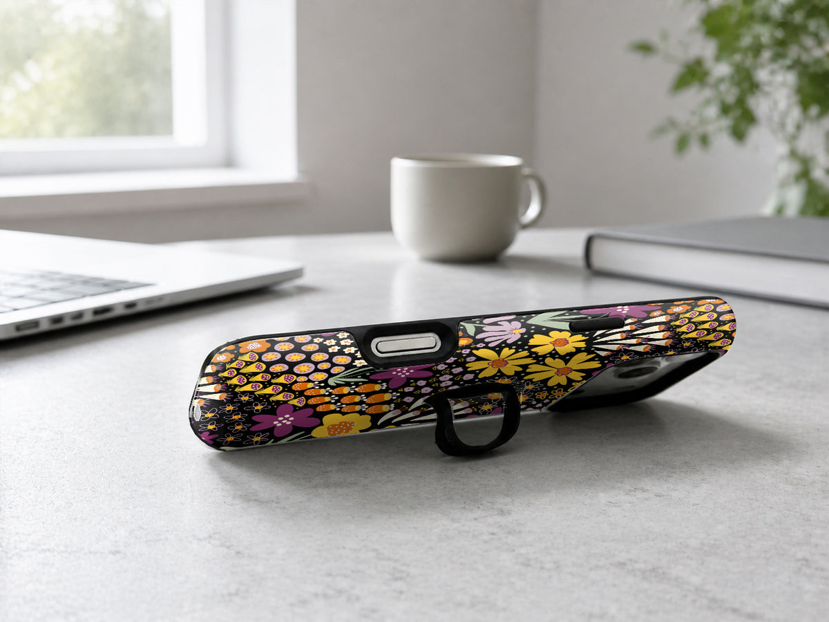 Black Folk Garden Floral MagSafe Loop iPhone Case shown in a neutral white professional lifestyle setting