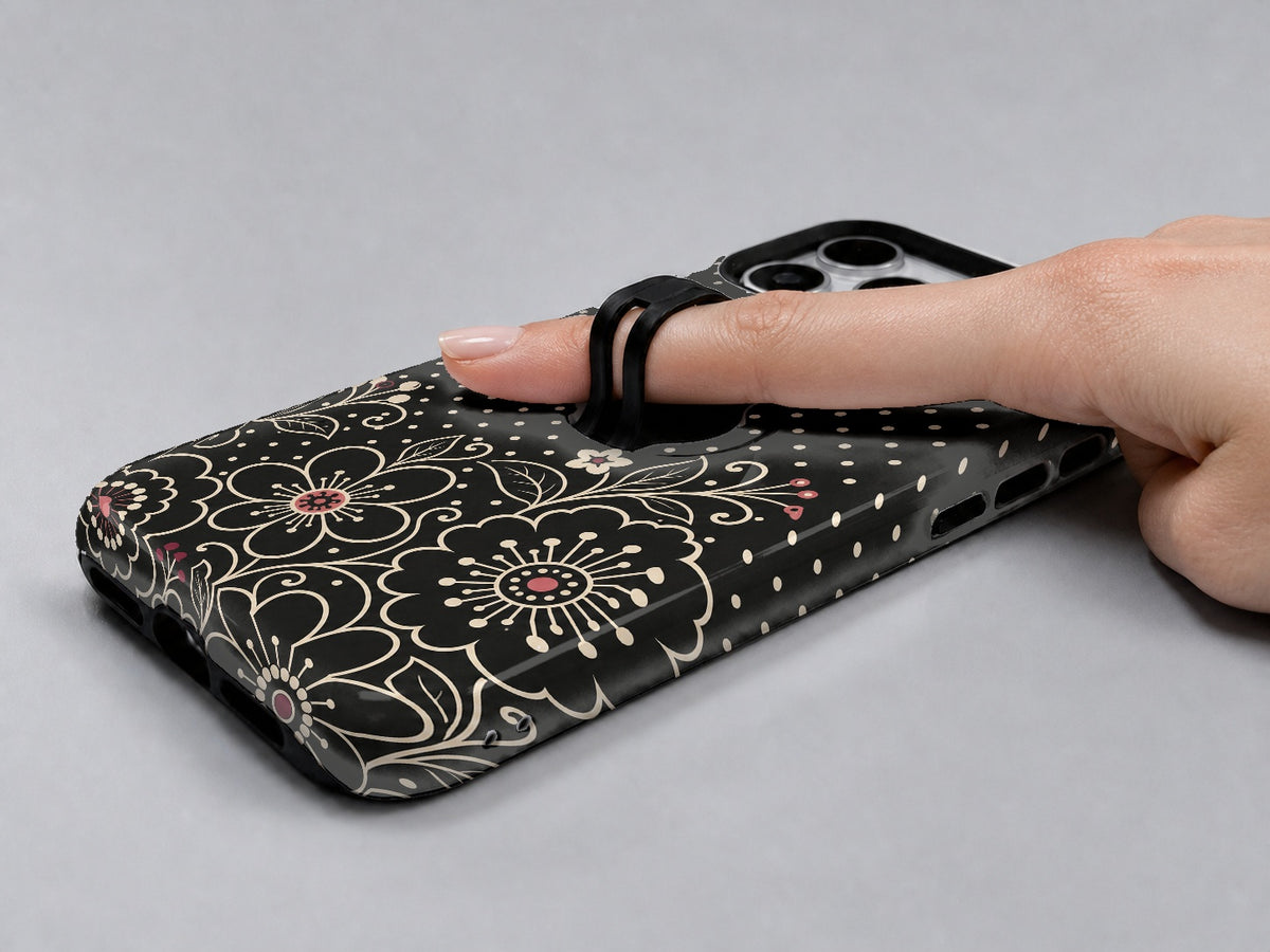 Black Pink Henna Floral MagSafe Loop iPhone Case shown in use with a finger through the horizontal loop