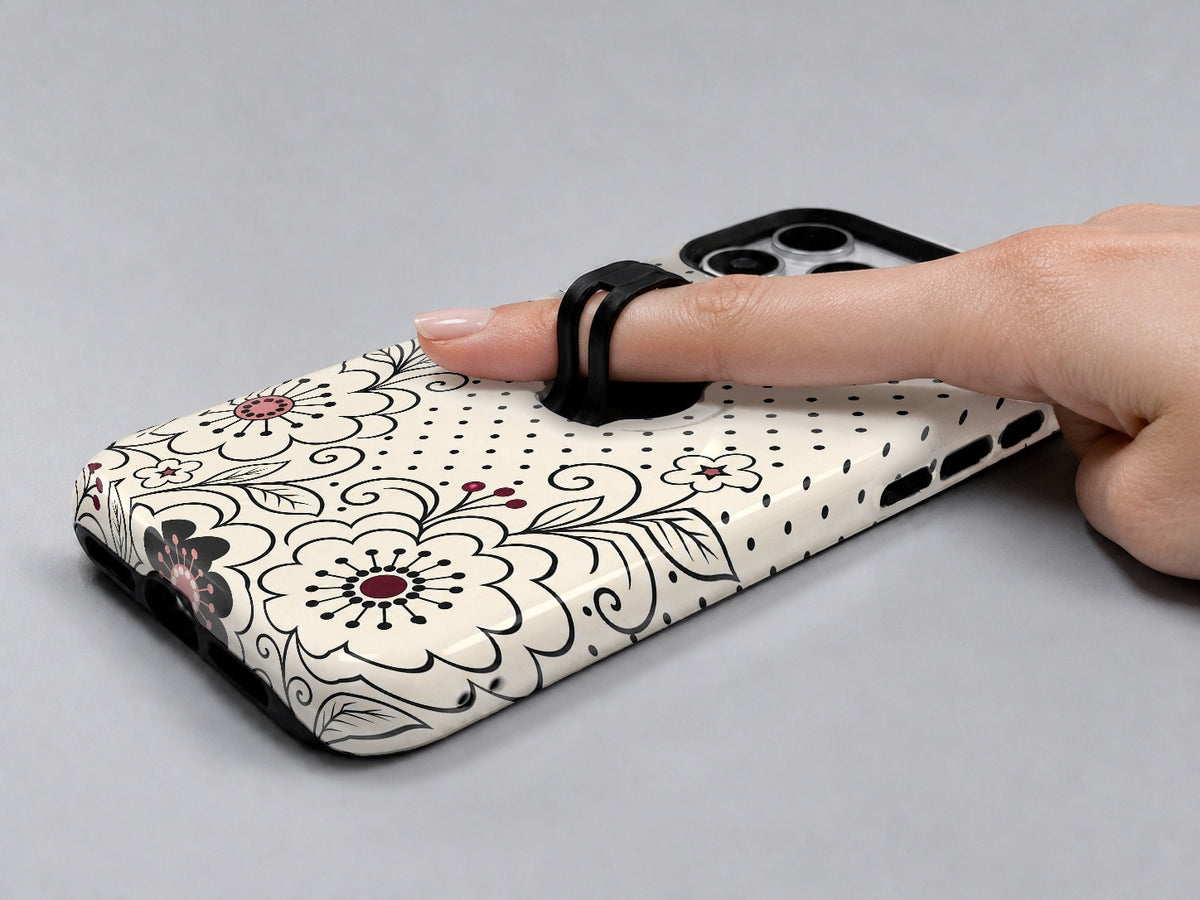 Black White Doodle Floral MagSafe Loop iPhone Case shown in use with a finger through the horizontal loop