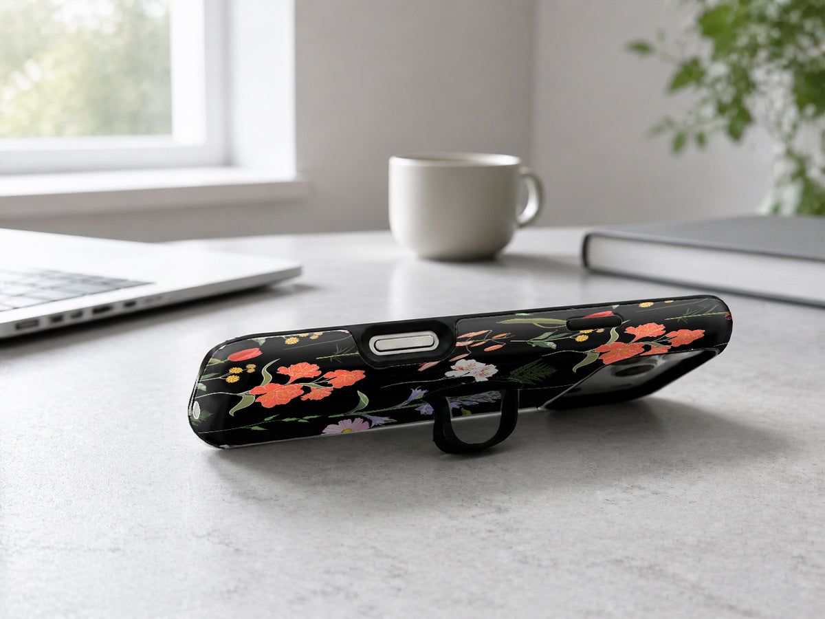 Black Wildflower Meadow MagSafe Loop iPhone Case shown in a neutral white professional lifestyle setting