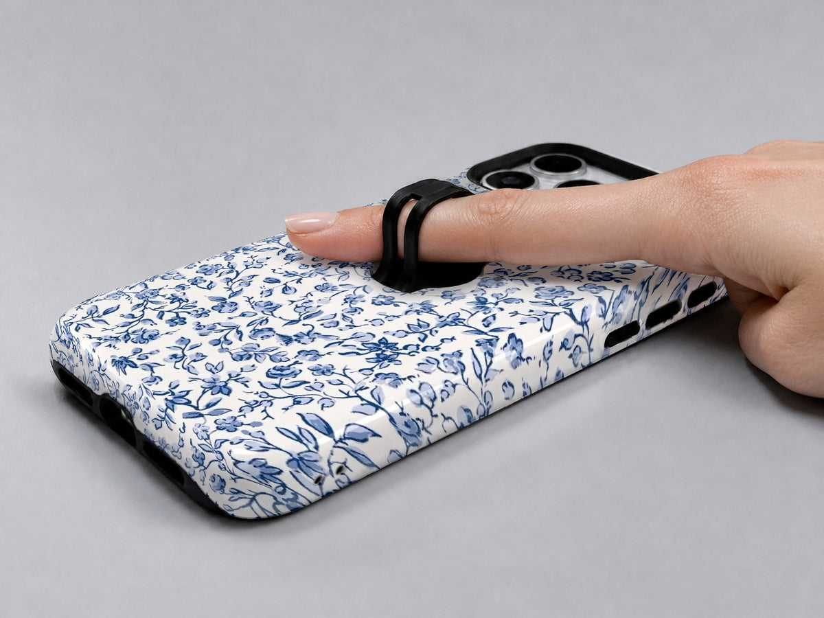 Blue Chinoiserie Floral MagSafe Loop iPhone Case shown in use with a finger through the horizontal loop