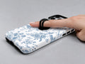 Blue Chinoiserie Rose MagSafe Loop iPhone Case shown in use with a finger through the horizontal loop