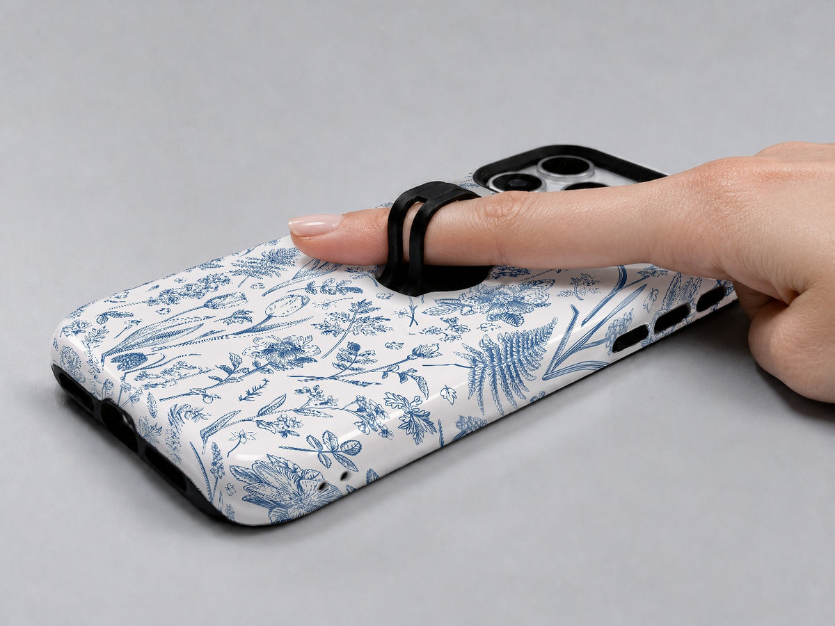 Blue Toile Wildflower MagSafe Loop iPhone Case shown in use with a finger through the horizontal loop