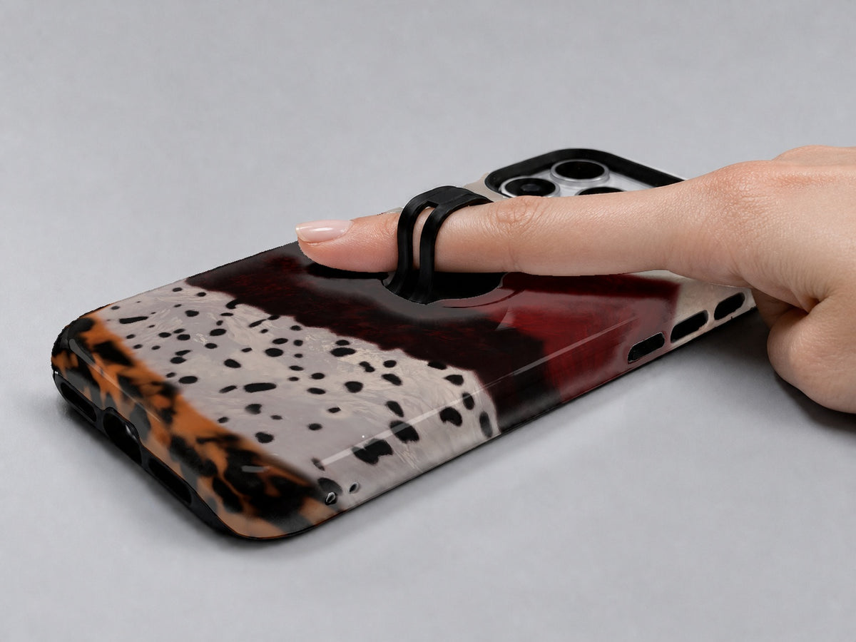 Burgundy Cream Abstract Animal Print MagSafe Loop iPhone Case shown in use with a finger through the horizontal loop