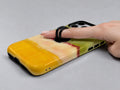 Chartreuse Cream Golden Yellow Color Block MagSafe Loop iPhone Case shown in use with a finger through the horizontal loop