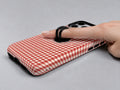 Cherry Red and White Gingham MagSafe Loop Case, shown with a finger through the loop