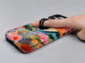 Colorful Abstract Landscape Floral MagSafe Loop iPhone Case shown in use with a finger through the horizontal loop