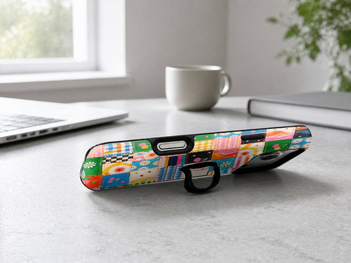 Colorful Folk Quilt Patchwork MagSafe Loop iPhone Case shown in a neutral white professional lifestyle setting