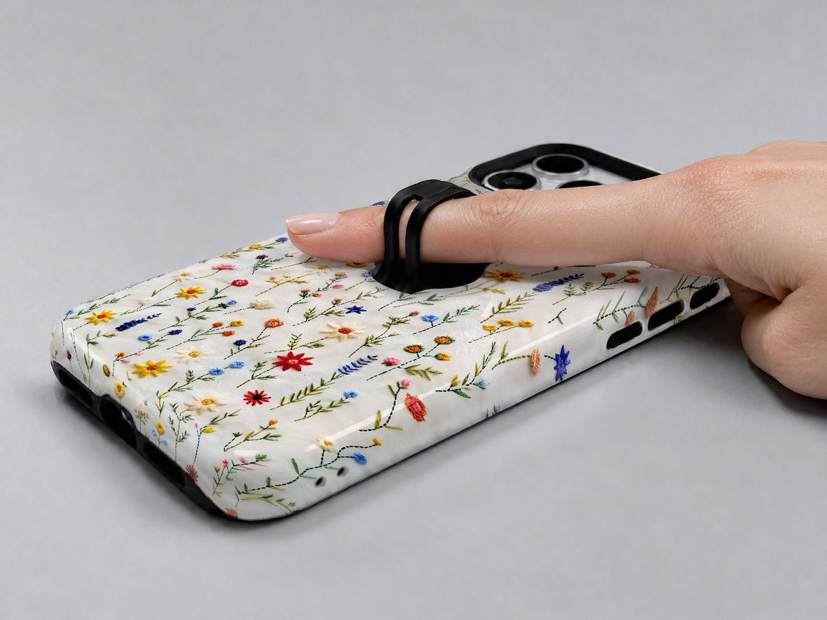 Colorful Pressed Wildflower MagSafe Loop iPhone Case shown in use with a finger through the horizontal loop