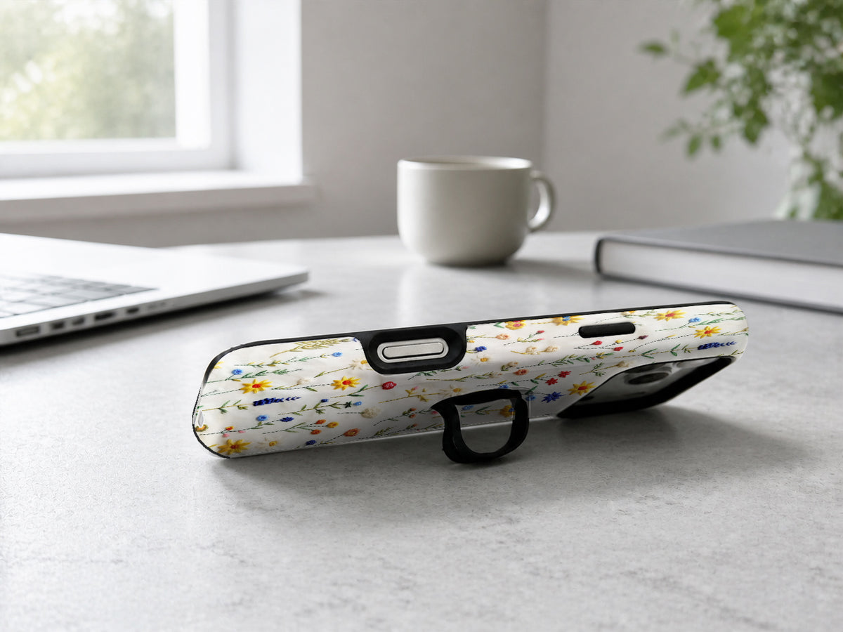 Colorful Pressed Wildflower MagSafe Loop iPhone Case shown in a neutral white professional lifestyle setting