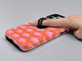 Coral Pink Scallop MagSafe Loop iPhone Case shown in use with a finger through the horizontal loop