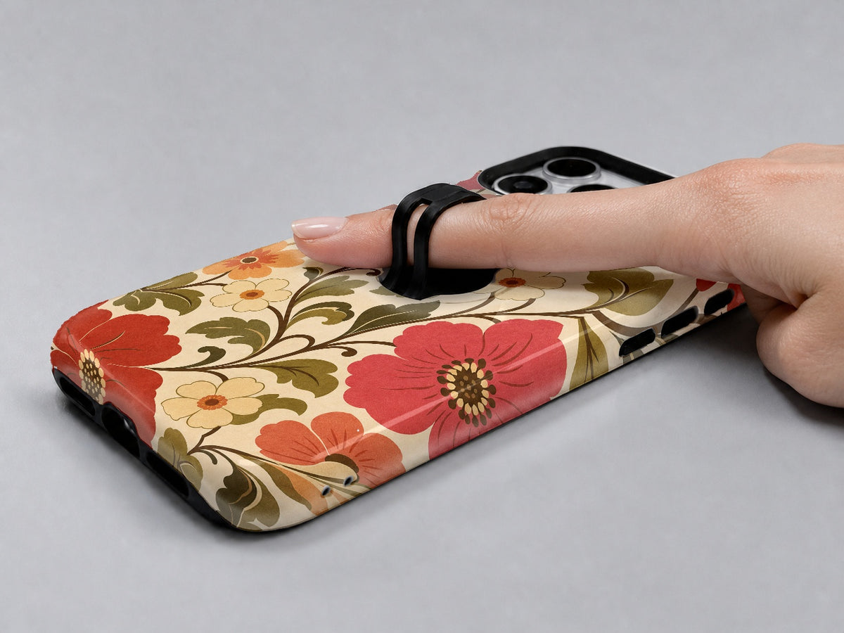 Coral Retro Folk Floral MagSafe Loop iPhone Case shown in use with a finger through the horizontal loop