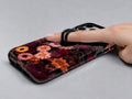Dark Autumn Daisy Floral MagSafe Loop iPhone Case shown in use with a finger through the horizontal loop