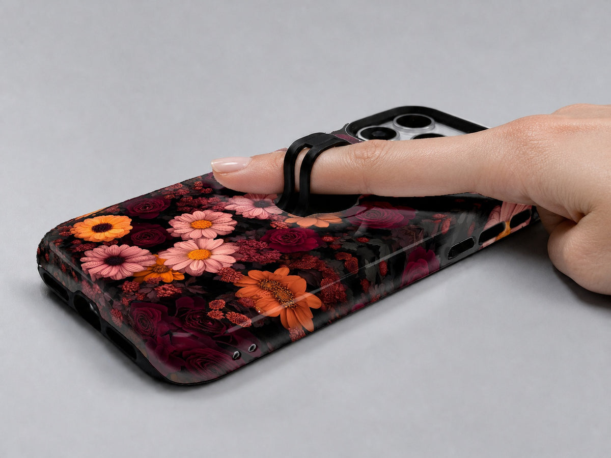 Dark Autumn Daisy Floral MagSafe Loop iPhone Case shown in use with a finger through the horizontal loop