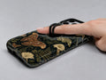 Dark Moth Botanical MagSafe Loop iPhone Case shown in use with a finger through the horizontal loop