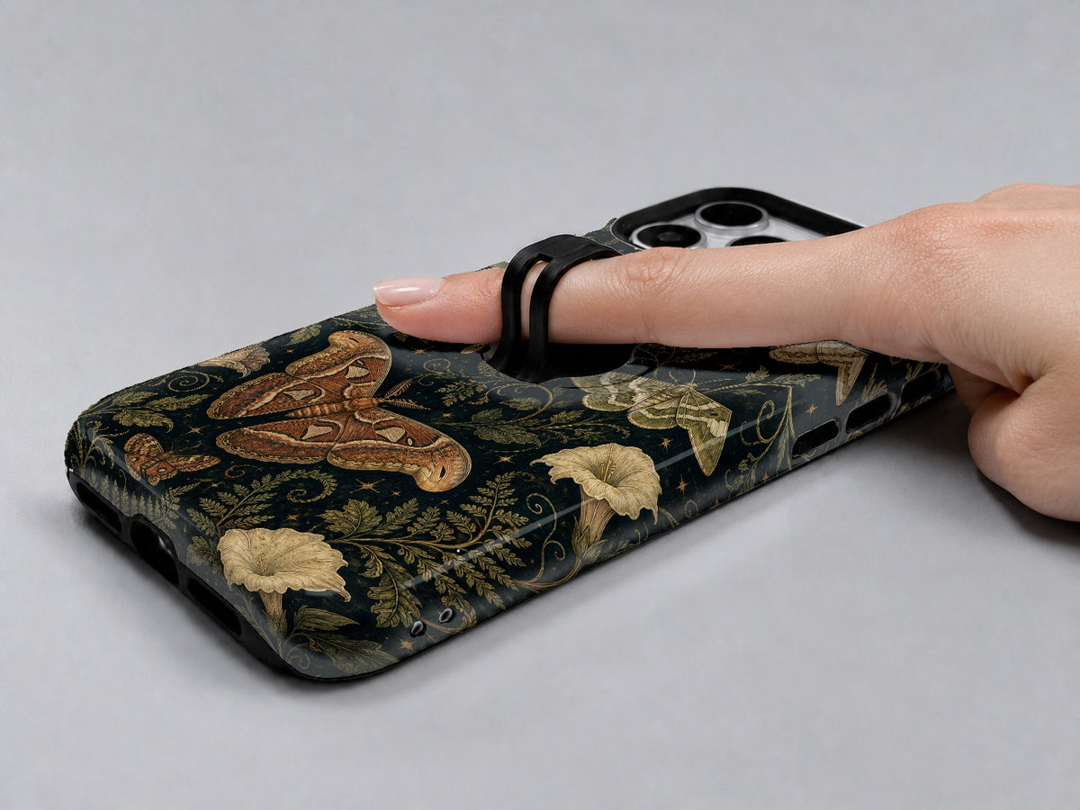 Dark Moth Botanical MagSafe Loop iPhone Case shown in use with a finger through the horizontal loop