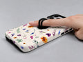 Delicate Mixed Wildflower MagSafe Loop iPhone Case shown in use with a finger through the horizontal loop