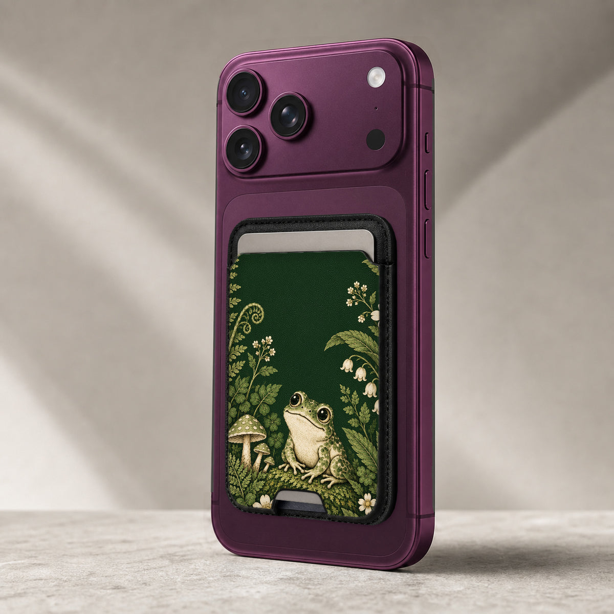 Forest Green Frog and Mushroom Garden MagSafe Card Holder, attached to the back of a compatible phone