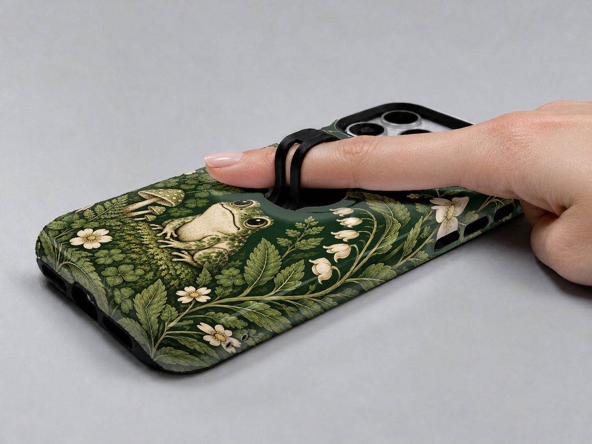 Forest Green Frog and Mushroom Garden MagSafe Loop iPhone Case, shown in use with a finger through the loop