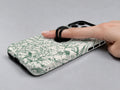 Green Toile Botanical MagSafe Loop iPhone Case shown in use with a finger through the horizontal loop