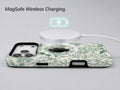 Green Toile Botanical MagSafe Loop iPhone Case shown with a MagSafe-compatible wireless charger attached