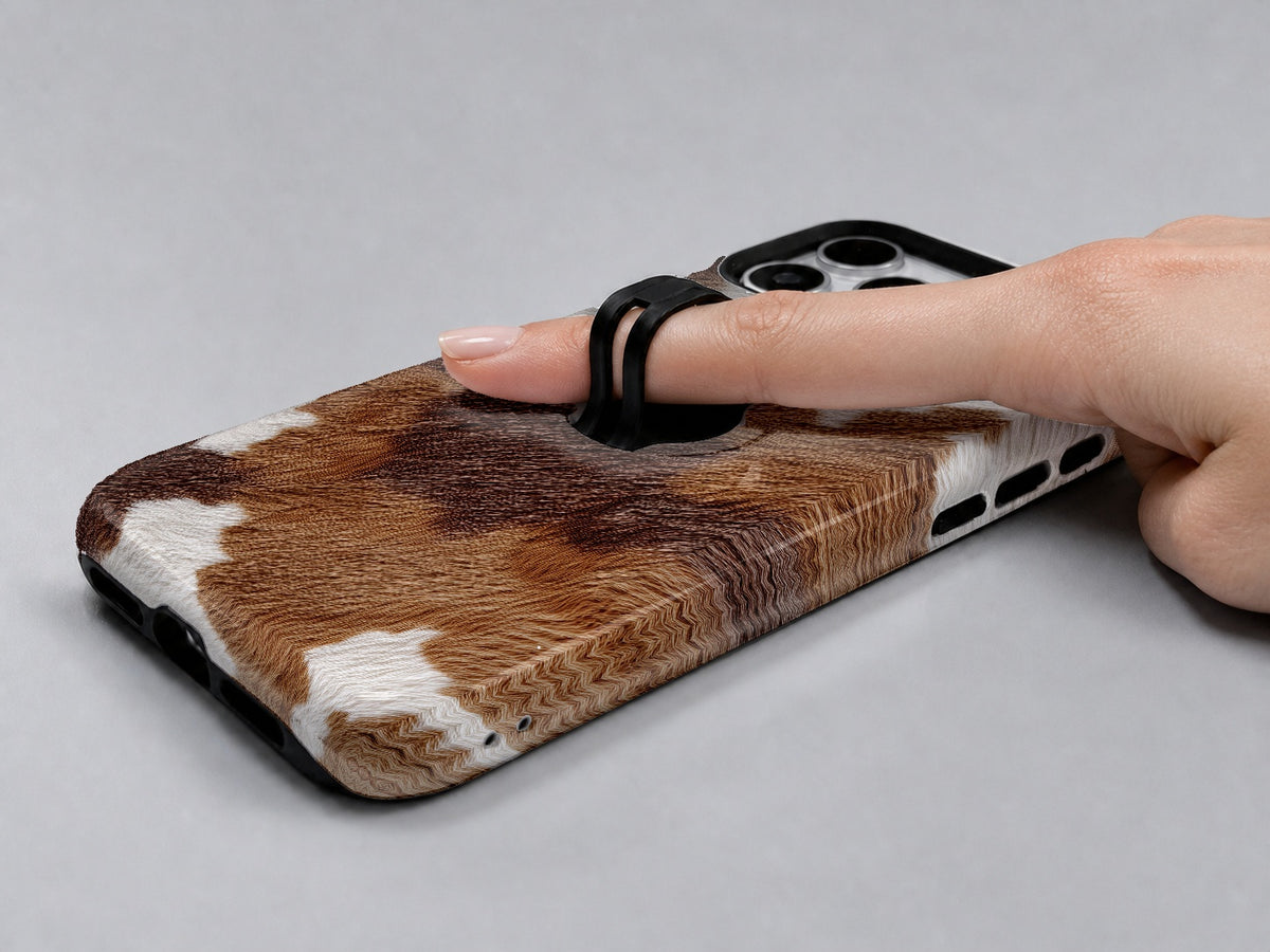Highland Cowhide Print MagSafe Loop iPhone Case shown in use with a finger through the horizontal loop
