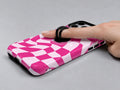 Hot Pink Wavy Checkerboard MagSafe Loop iPhone Case shown in use with a finger through the horizontal loop