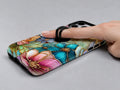 Jewel Tone Stained Glass Floral MagSafe Loop iPhone Case shown in use with a finger through the horizontal loop