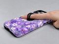 Lavender Daisy Floral MagSafe Loop iPhone Case shown in use with a finger through the horizontal loop