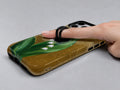 Lily of the Valley on Gold MagSafe Loop iPhone Case shown in use with a finger through the horizontal loop
