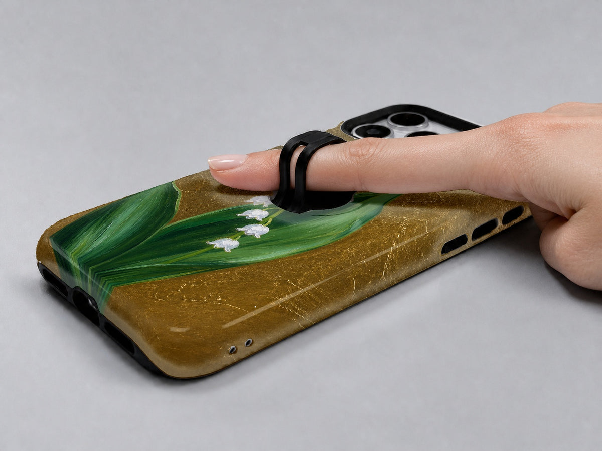 Lily of the Valley on Gold MagSafe Loop iPhone Case shown in use with a finger through the horizontal loop