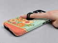 Mint Retro Folk Floral MagSafe Loop iPhone Case shown in use with a finger through the horizontal loop