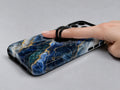 Navy Gold Marble MagSafe Loop iPhone Case shown in use with a finger through the horizontal loop