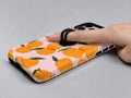 Orange Fruit on Pink MagSafe Loop iPhone Case shown in use with a finger through the horizontal loop