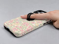 Pastel Cottage Garden Floral MagSafe Loop iPhone Case shown in use with a finger through the horizontal loop