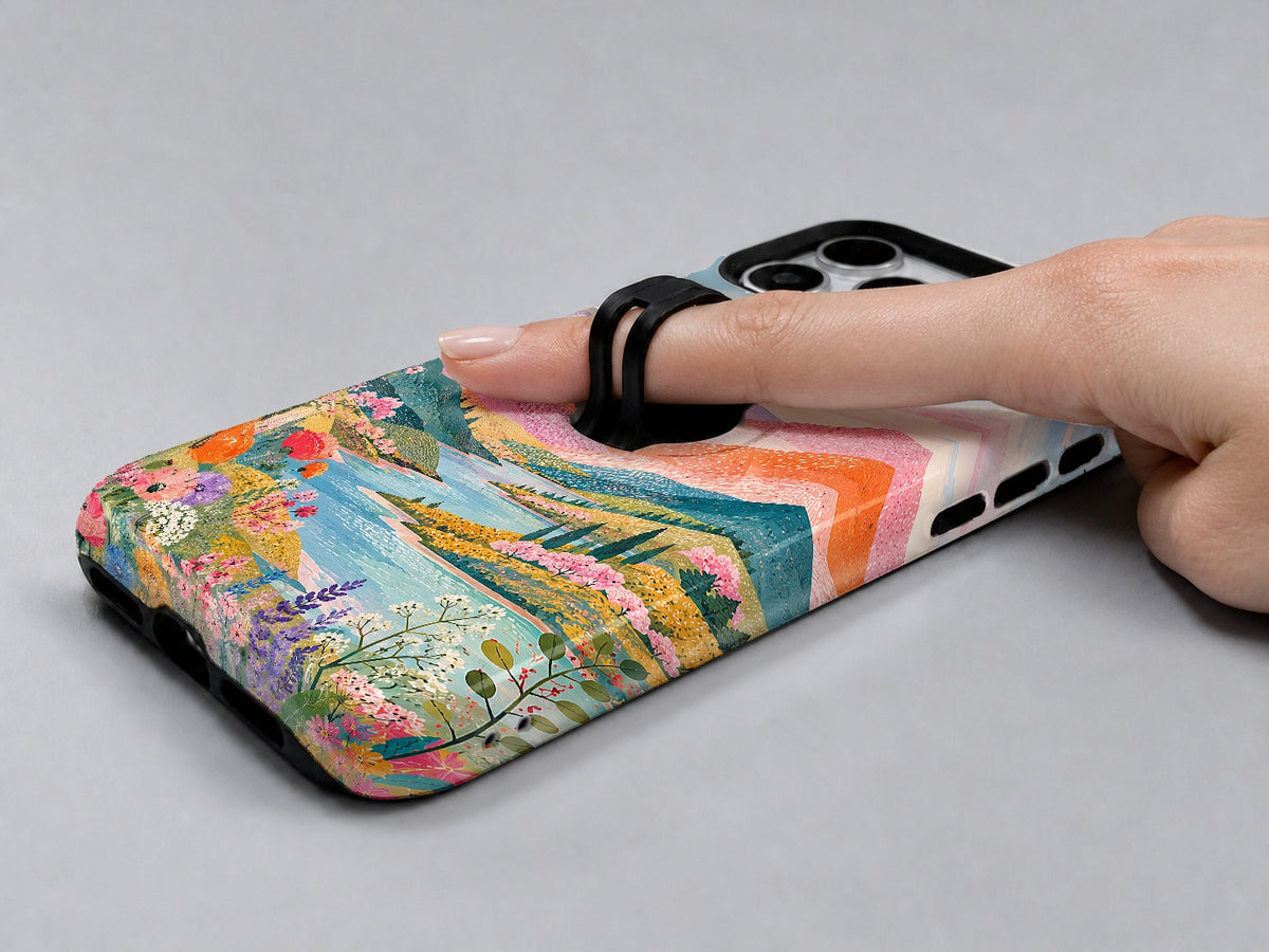 Pastel Painted Meadow Landscape MagSafe Loop iPhone Case shown in use with a finger through the horizontal loop
