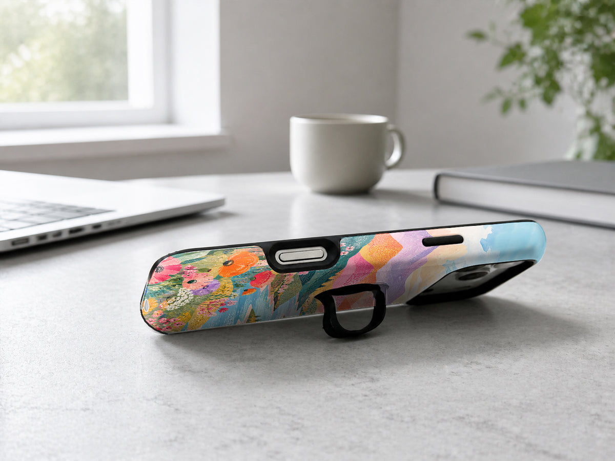Pastel Painted Meadow Landscape MagSafe Loop iPhone Case shown in a neutral white professional lifestyle setting