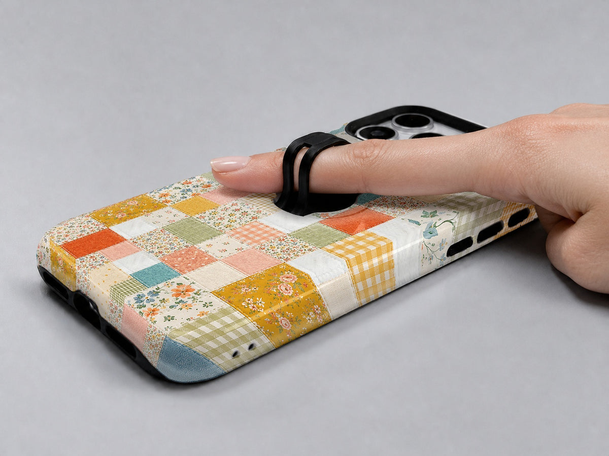 Pastel Quilt Patchwork MagSafe Loop iPhone Case shown in use with a finger through the horizontal loop