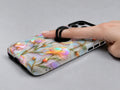 Pastel Tulip Stained Glass MagSafe Loop iPhone Case shown in use with a finger through the horizontal loop
