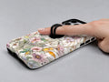 Pastel Wildflower Stained Glass MagSafe Loop iPhone Case shown in use with a finger through the horizontal loop