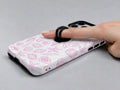 Pink Coastal Seashell MagSafe Loop iPhone Case shown in use with a finger through the horizontal loop