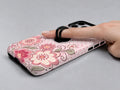 Pink Retro Doodle Floral MagSafe Loop iPhone Case shown in use with a finger through the horizontal loop