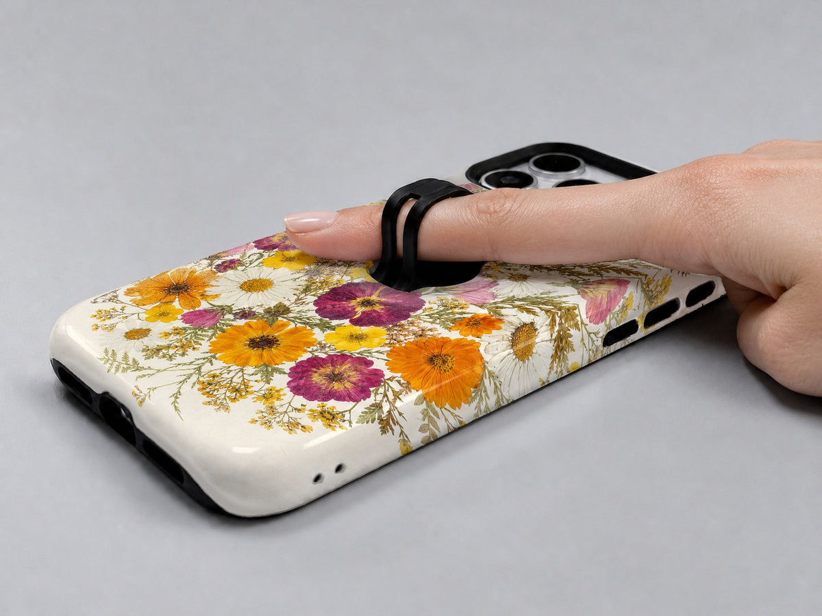 Pressed Daisy Wildflower Bouquet MagSafe Loop iPhone Case shown in use with a finger through the horizontal loop
