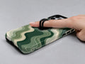 Sage Green Layered Waves MagSafe Loop iPhone Case shown in use with a finger through the horizontal loop