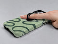 Sage Green Retro Swirl MagSafe Loop iPhone Case shown in use with a finger through the horizontal loop