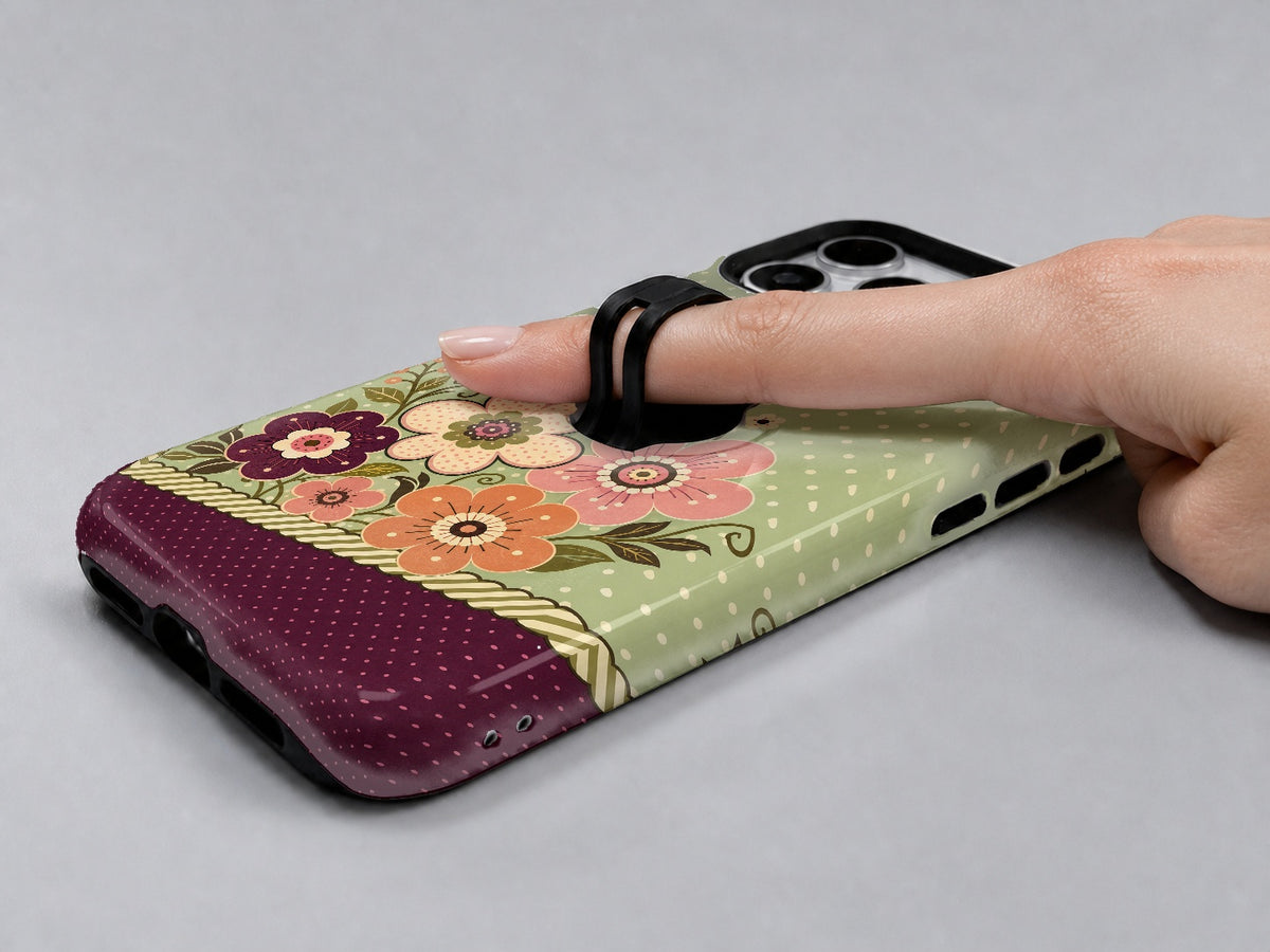 Sage Retro Folk Floral MagSafe Loop iPhone Case shown in use with a finger through the horizontal loop